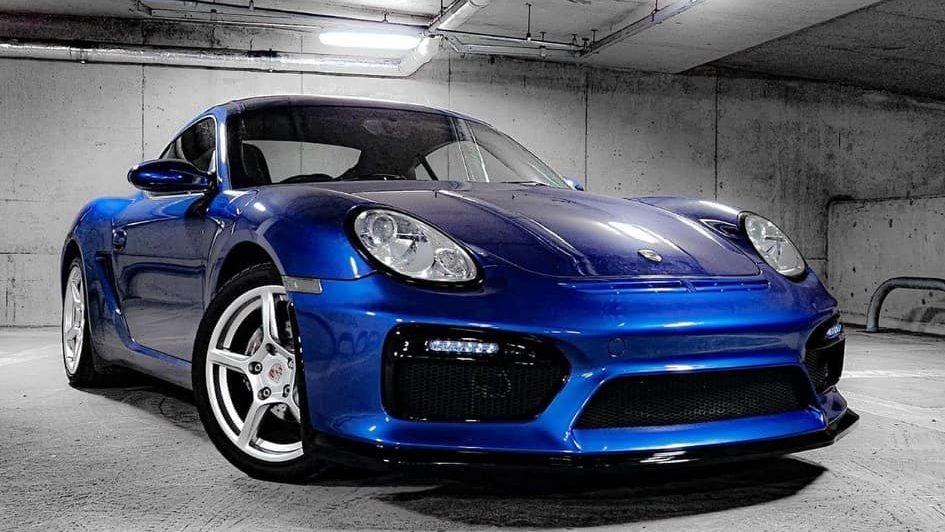 A blue sports car parked in a dimly lit underground parking garage, showcasing its sleek design and shiny wheels.